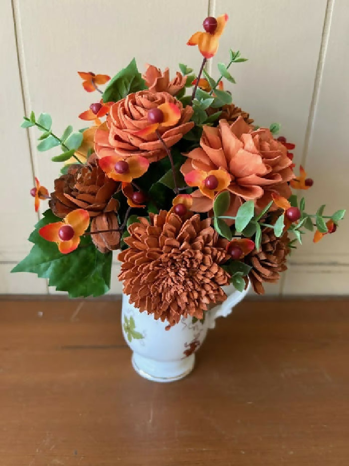 White cup with orange grapes on it, green and orange filler, and burnt orange and orange Sola Wood flowers.